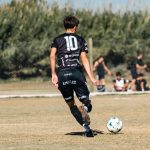 A dynamic soccer scene with young athletes striving for the ball in a local match outdoors.